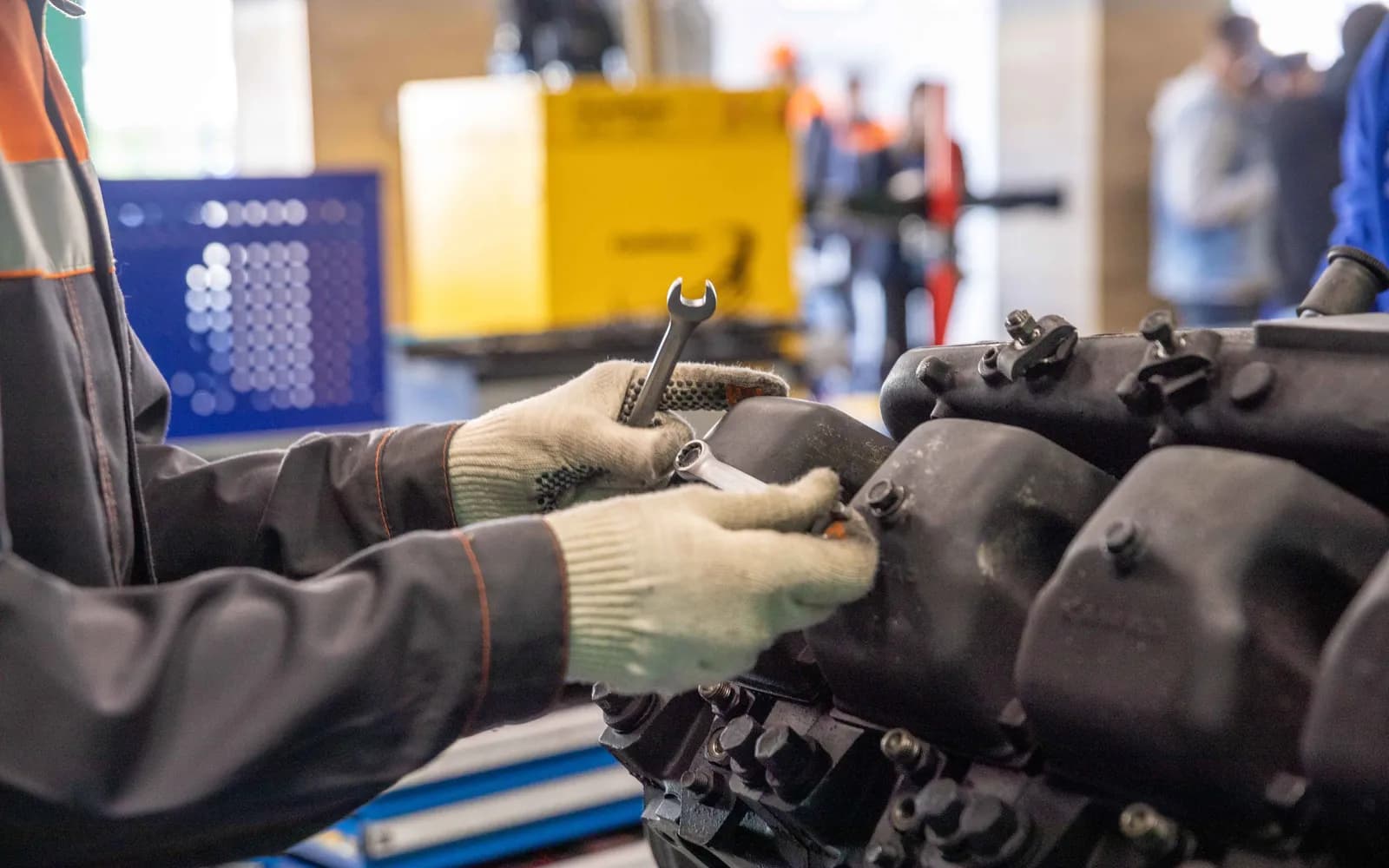 Mains d'un technicien serrant une pièce à la clé en atelier